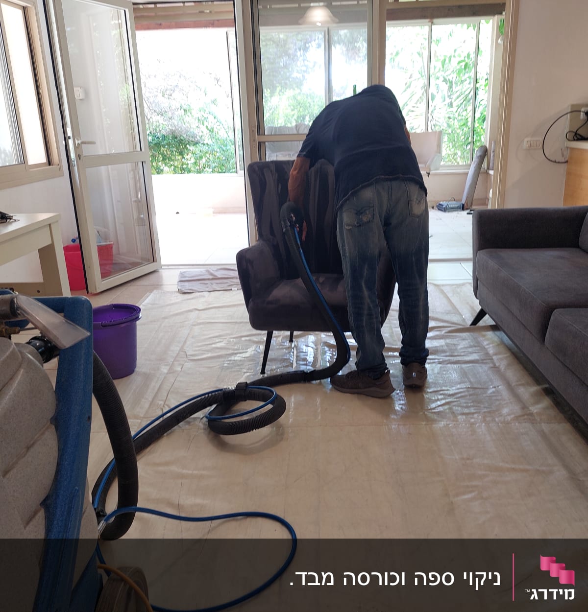 אדם מנקה ספה עם מכונת ניקוי ושואב אבק